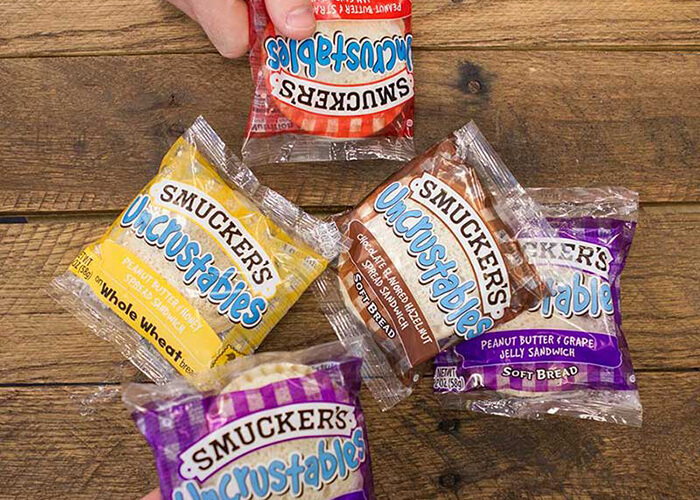 Variety of Smuckers Uncrustable Flavors On Wooden Table